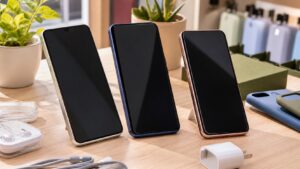 Three unbranded affordable smartphones with blank screens arranged on a bright tabletop